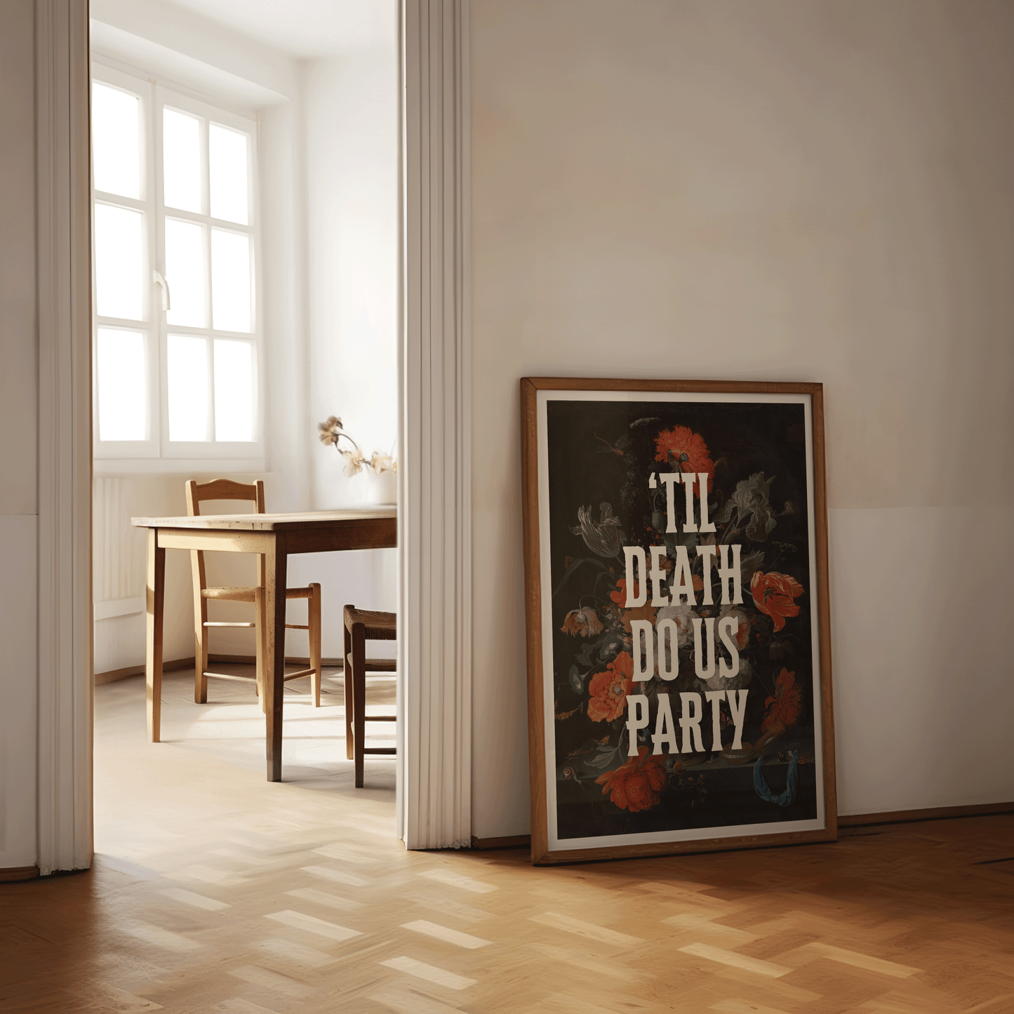 Framed poster with 'Til Death Do Us Party' text on a dramatically dark, vintage floral painting, in a room with wooden floor and table.