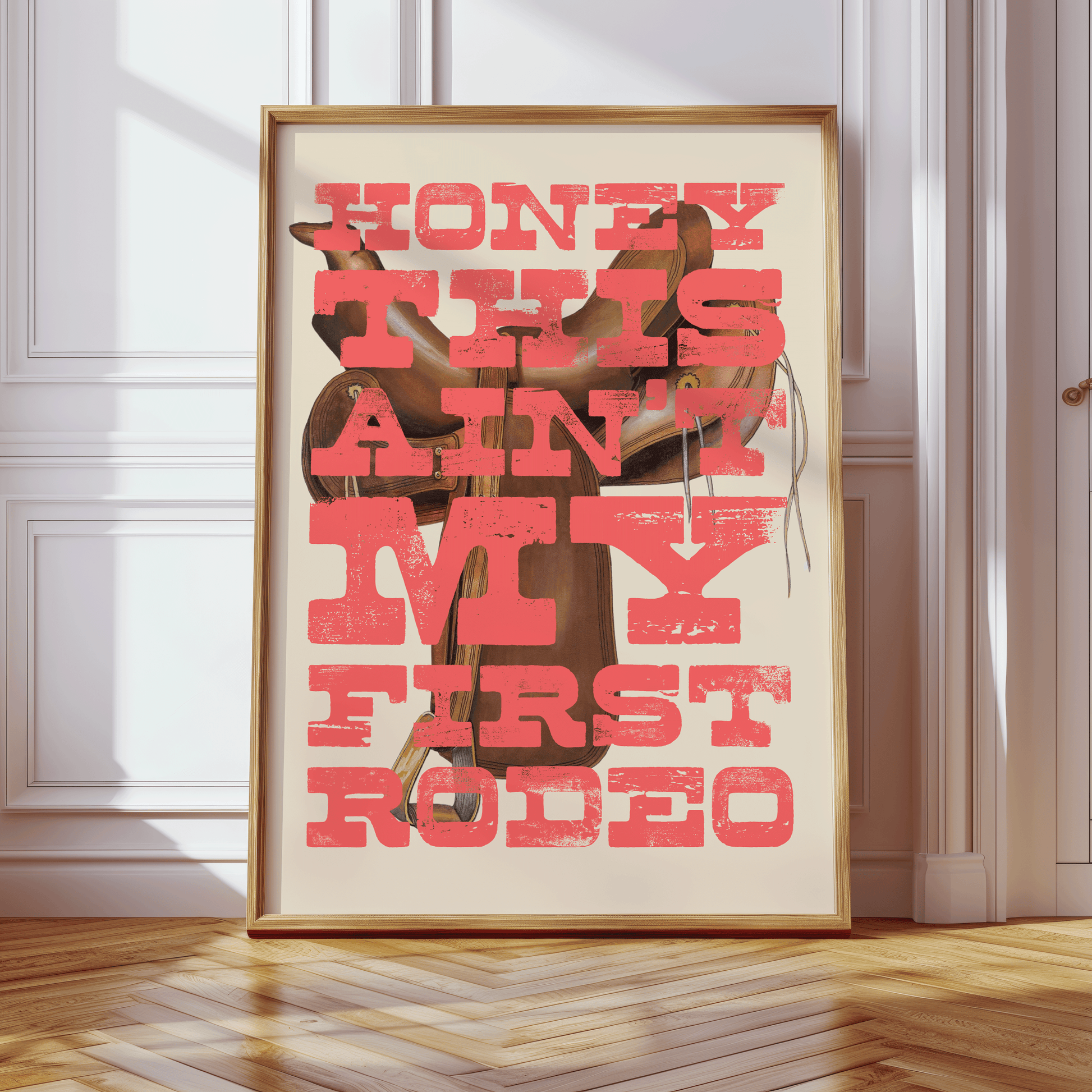 Vintage saddle illustration with HONEY THIS AIN'T MY FIRST RODEO, written in distressed western style font, in peachy-red capital letters, quirky gallery wall art print